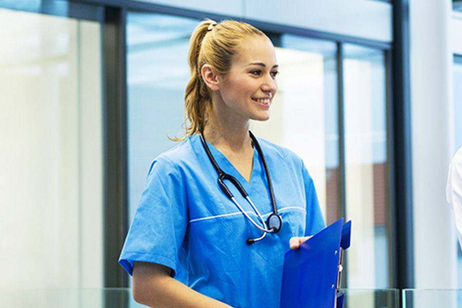 A nurse holding a file folder. She has a stethoscope hanging around her neck.